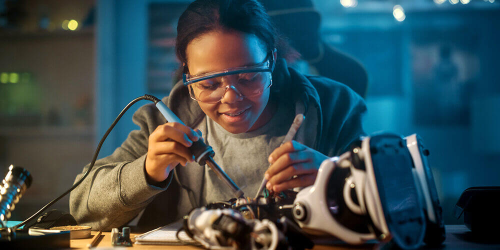 Female technician repairing electronic equipment using a soldering iron.