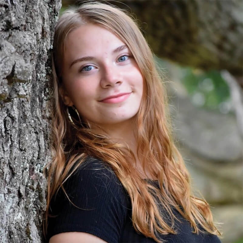 Photo of Eberly Tirillo leaning against a tree.