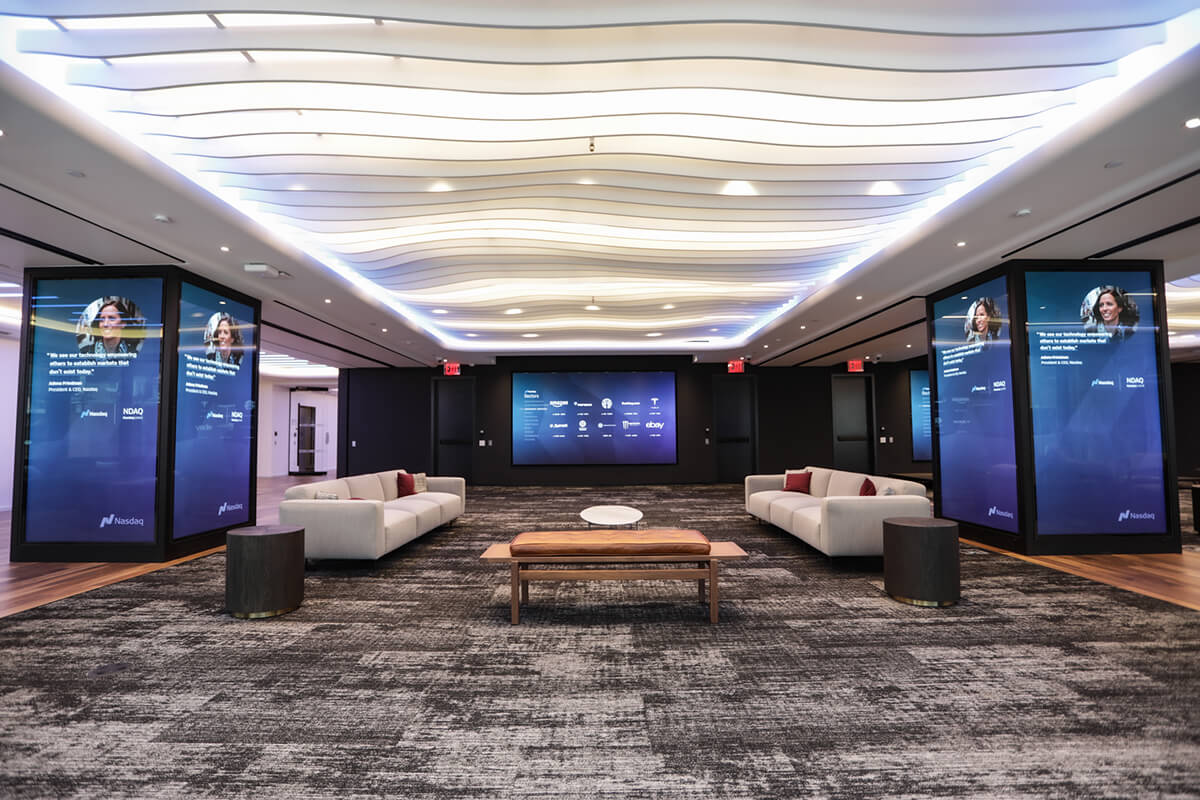 Video walls surrounding white sofas in the lobby of the NASDAQ in New York City.