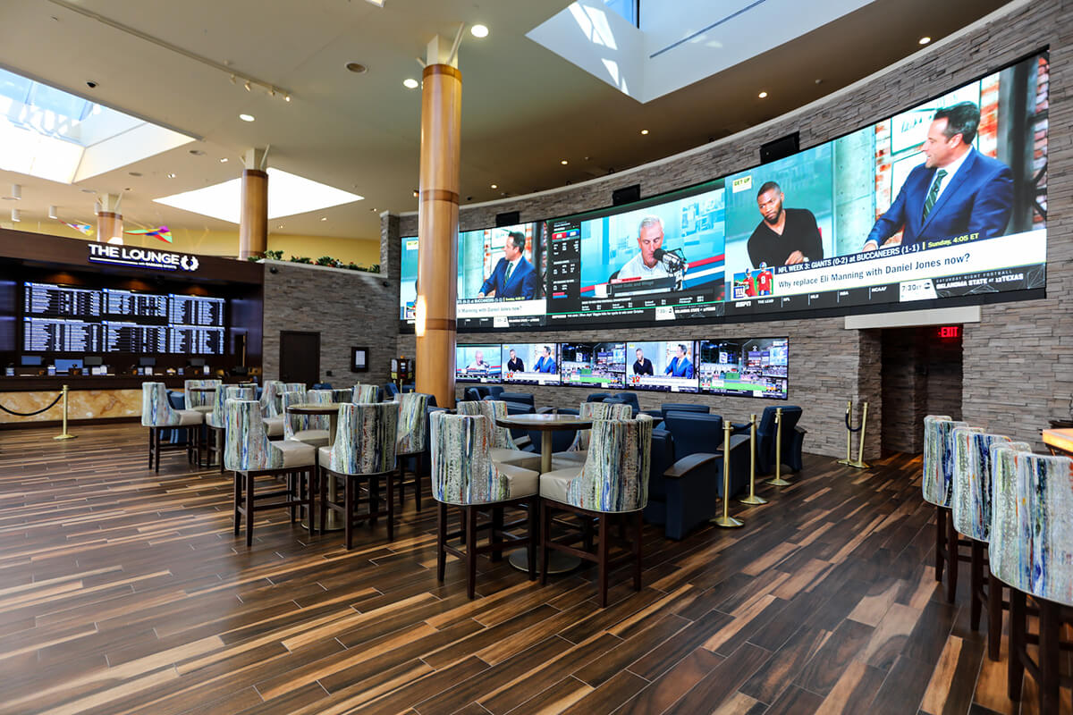 Video wall and seating inside The Lounge at Caesars Sportsbook at Turning Stone Resort Casino.