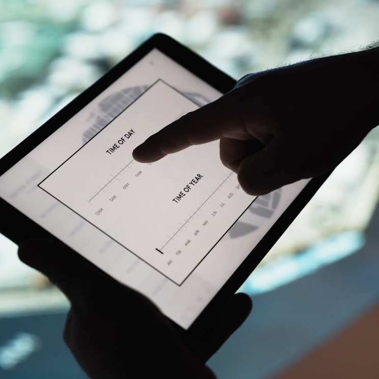 A hand interacts with a digital display on a tablet showing a time graph.