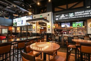 A sports bar and restaurant with video walls displaying scores and TVs with games playing.