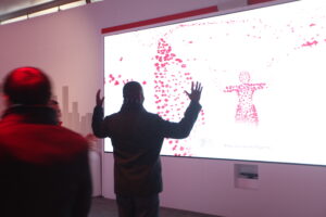 A man standing in front of a projector screen that shows his body’s heat signature.