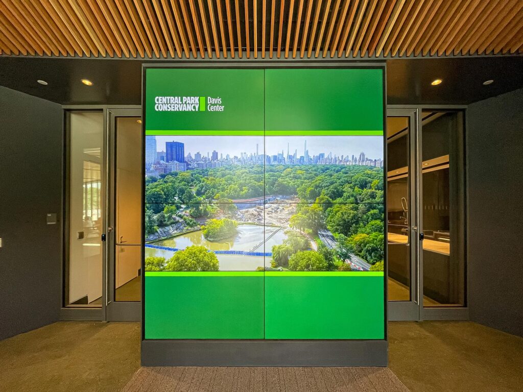 Wide view of Central Park from above displayed on green-framed video wall