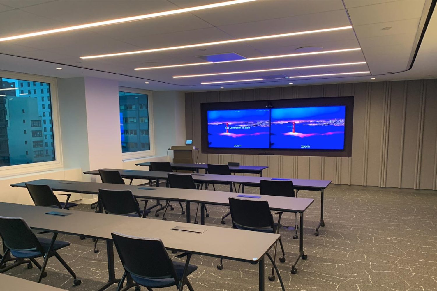 A sleek training room with dual screens for presentations and a podium at the front.