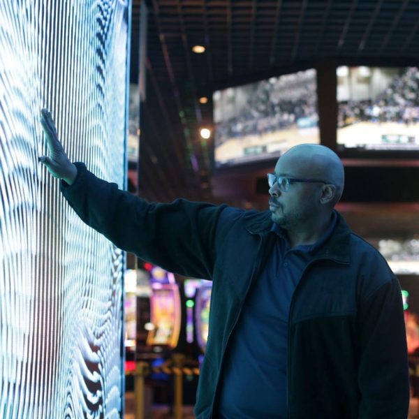 Man interacting with a large illuminated digital screen in a modern setting