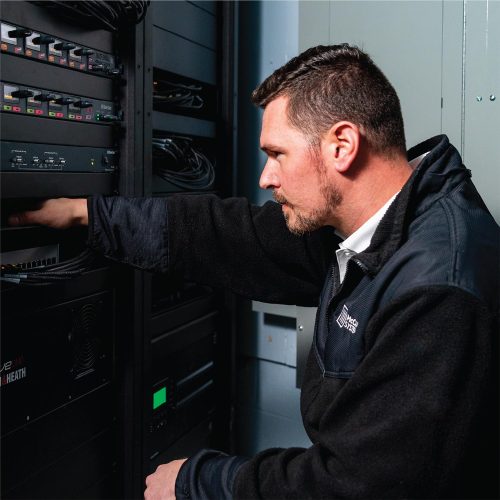 Engineer adjusting AV equipment in a professional rack setup