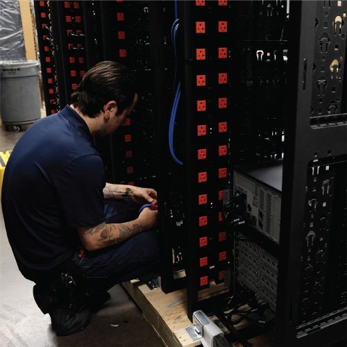 Technician kneeling and wiring power distribution units in server rack