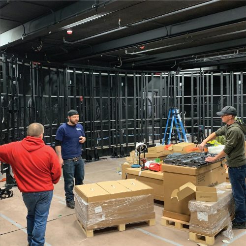 Team of technicians preparing AV equipment for installation in large room