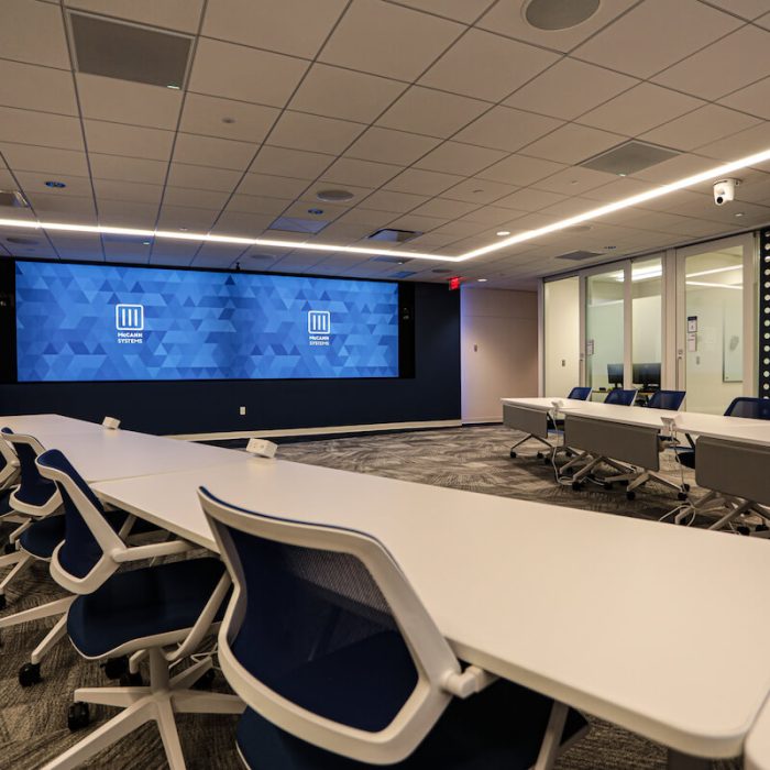 Briar Ridge conference room showing two screens with McCann logos, chairs and tables.