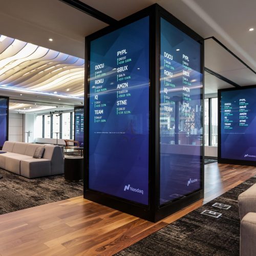 An office area with large digital displays showing stock market information.