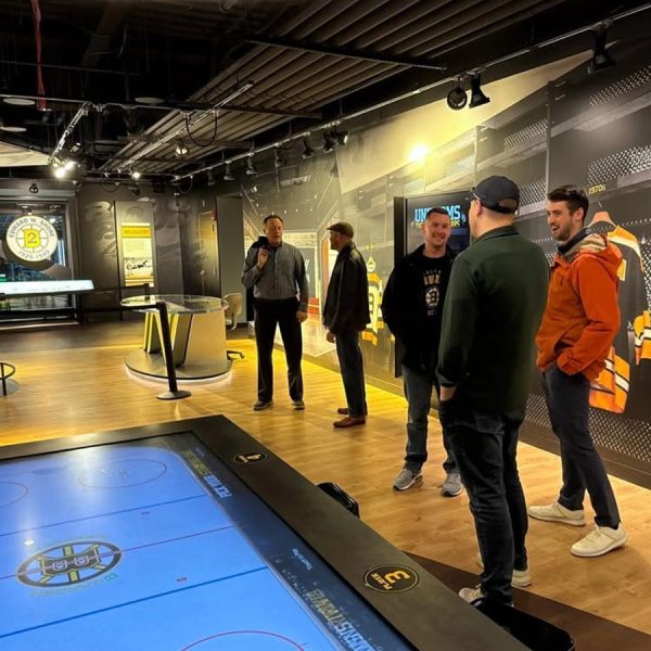 cta-casinos-sportsbooks Group of people talking near a digital air hockey table in a sports-themed exhibit