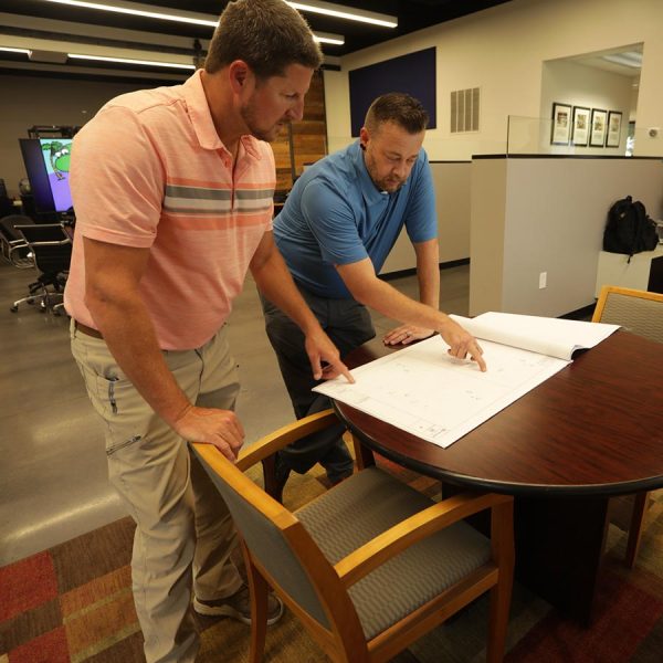 cta-challenge Two men reviewing technical plans on a table in a modern office
