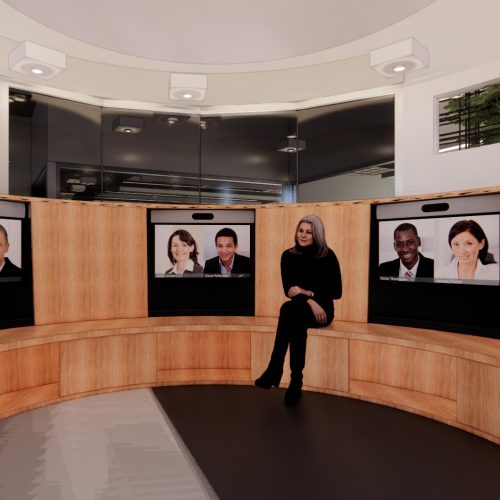 A woman sits in a modern meeting room with curved wooden seating and screens showing virtual participants.