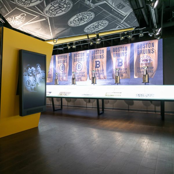 A sports exhibit showcasing championship banners and trophies with a display screen on the left.