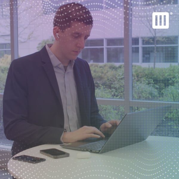 Man in a business suit working on a laptop with two smartphones on the table.