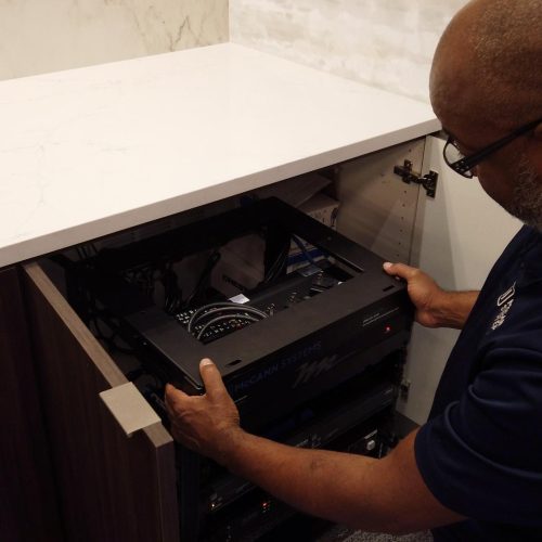 A man installing equipment inside a cabinet.