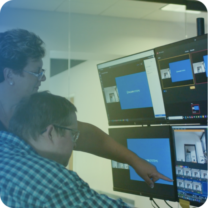 Two technicians working together and pointing at a monitor.