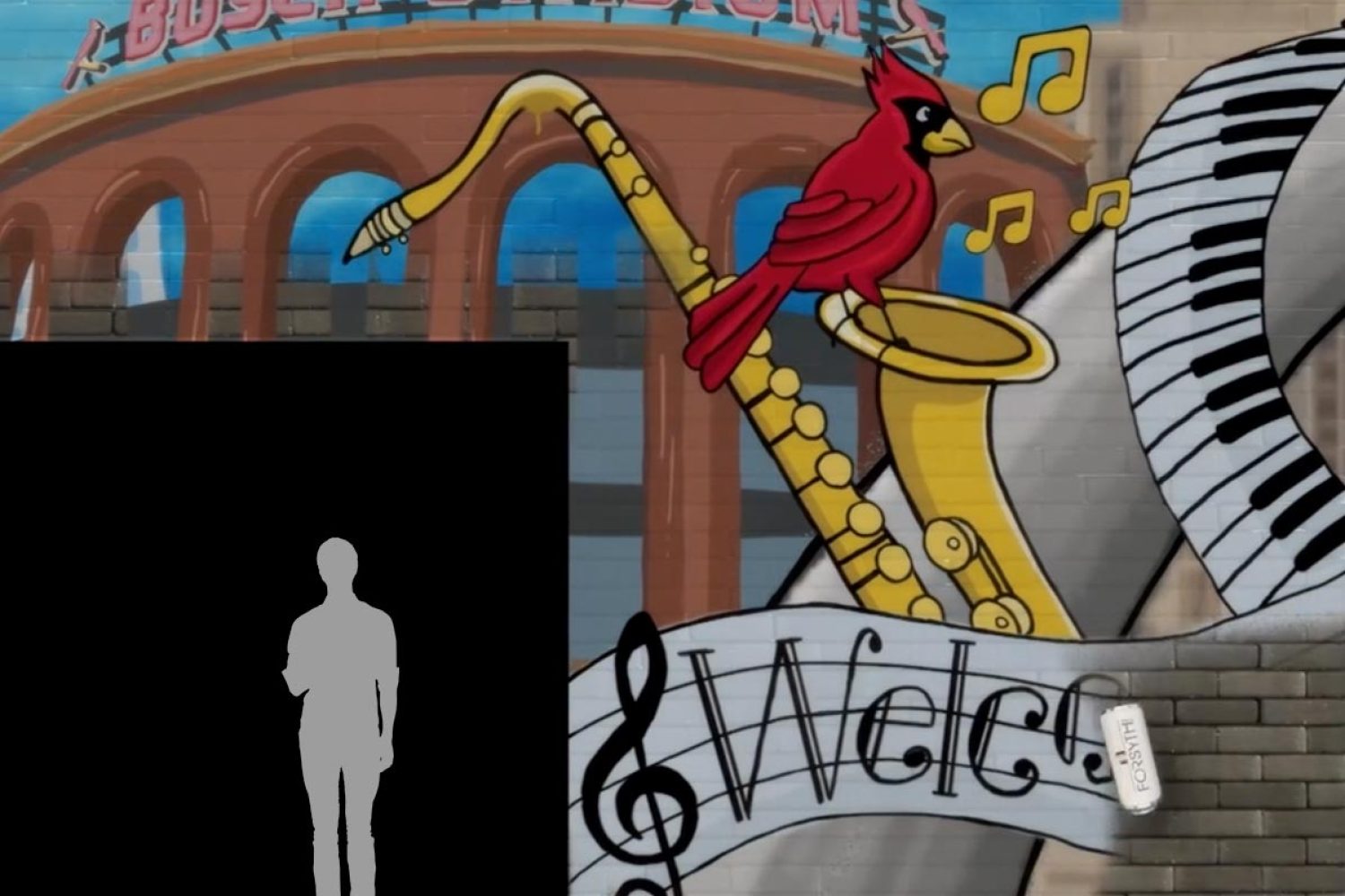 A colorful mural of a red bird playing a saxophone in front of an archway with musical notes and the word "Welcome."